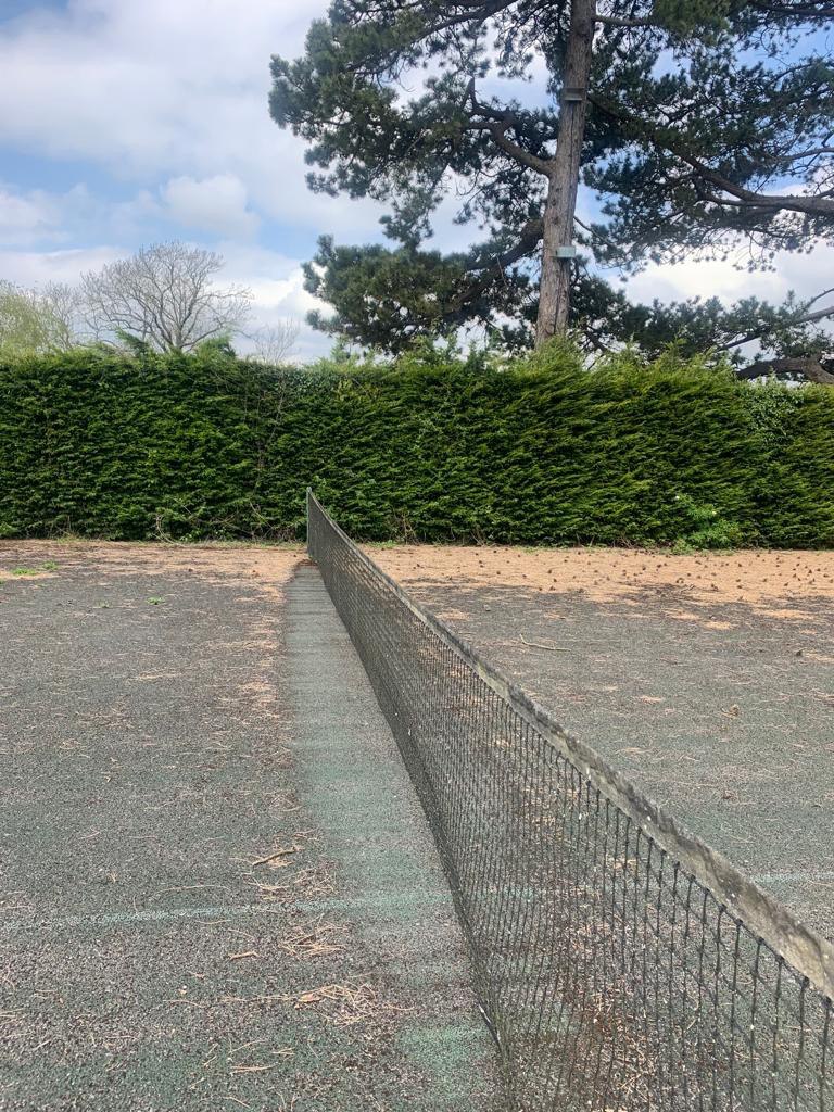 This is a photo of a tennis court in Surrey that is in need of refurbishment