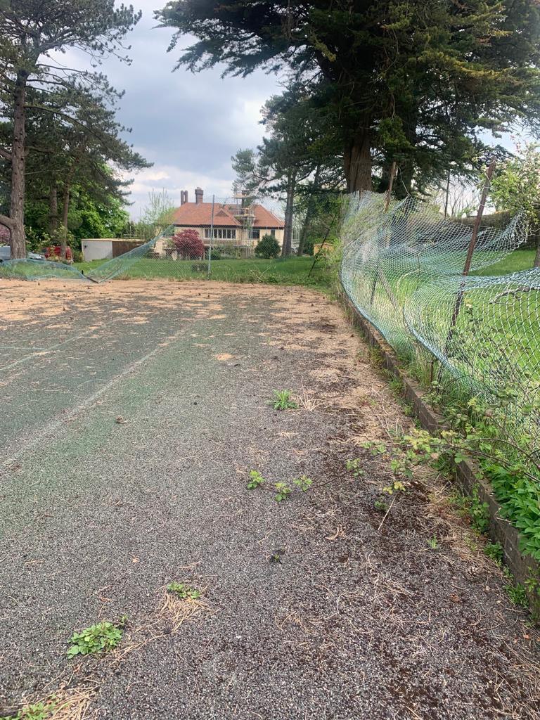 This is a photo of a tennis court in Surrey that is in need of refurbishment