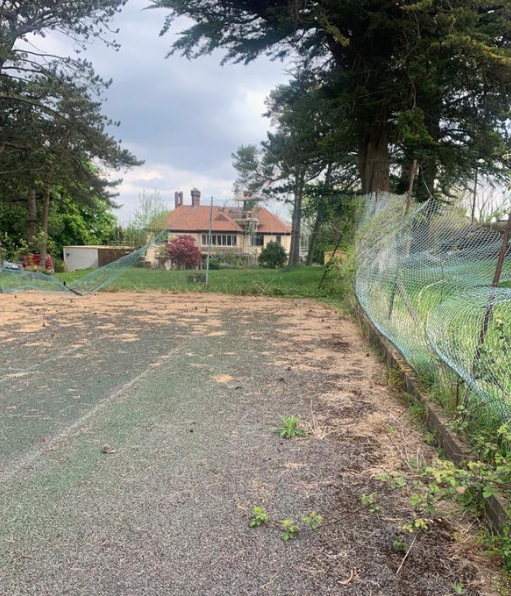 This is a photo of a tennis court in Surrey that is in need of refurbishment